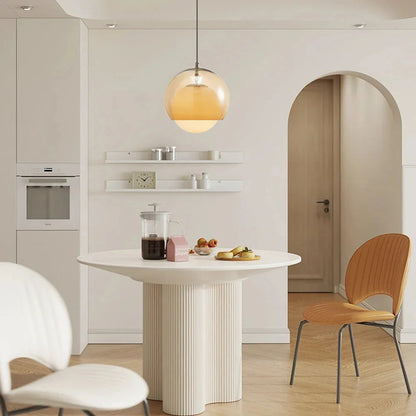 Pendant Globe Light in a modern kitchen with a round white table and wooden chairs.