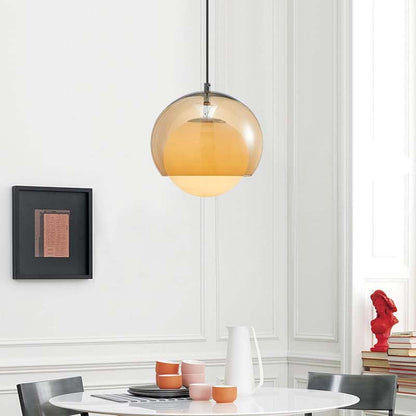 Modern pendant light hanging above a dining table with decor items.