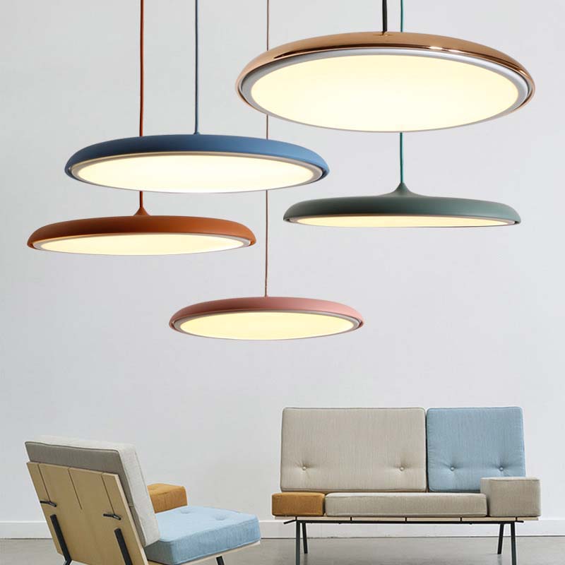 The colorful Luna Pendant Lamp and Macaron Pendant Light hang above a modern living room furnished with a sofa and armchairs.