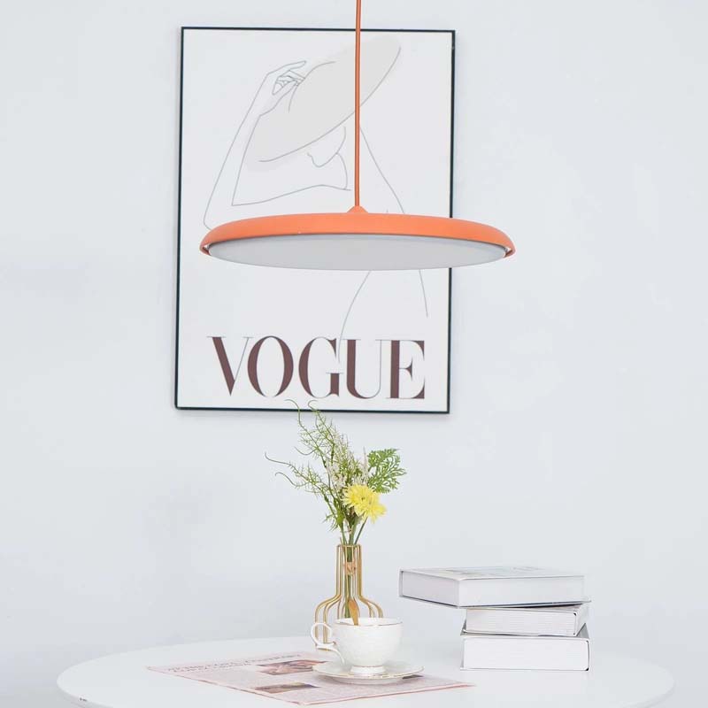 Pendant Lamp Luna. Wini Macaron 4 Lunrlighting with a coral lampshade over a table with a vase of flowers and books on a white wall with a Vogue magazine poster.
