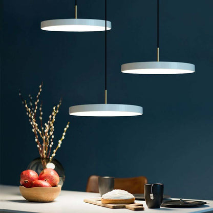 Three pendant lights hanging above a dining table with a dark blue wall background.