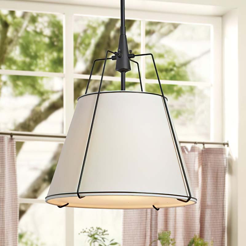 Pendant light with white shade and black frame hanging in a room with windows and curtains.