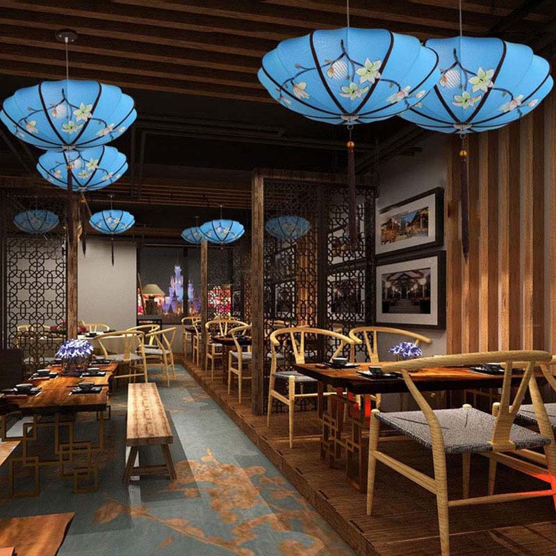 Restaurant interior with wooden furniture, blue floral pendant lights, and decorative wall art.