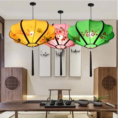 Three colorful paper lanterns hanging in a room with wooden furniture and artwork on the wall.