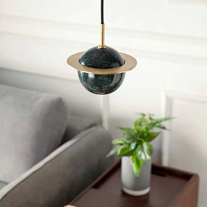 Decorative pendant light with green marble-like shade and gold accents in a living room setting.