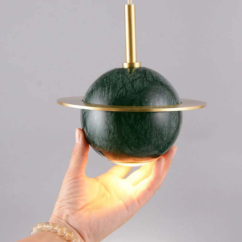 Green marble pendant light held by a hand against a gray background