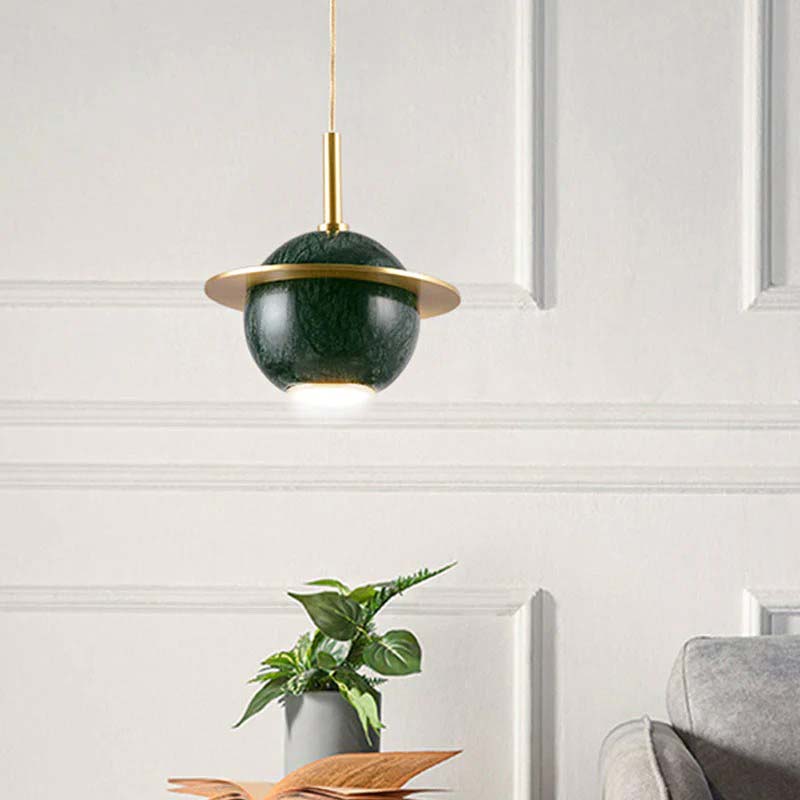 Modern pendant light with green shade and gold accents in a room setting.