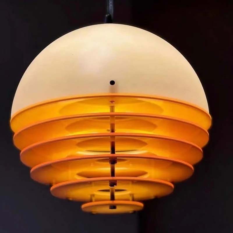 Pendant lamp Sunset with a dome-shaped shade and layered rings emitting warm light.