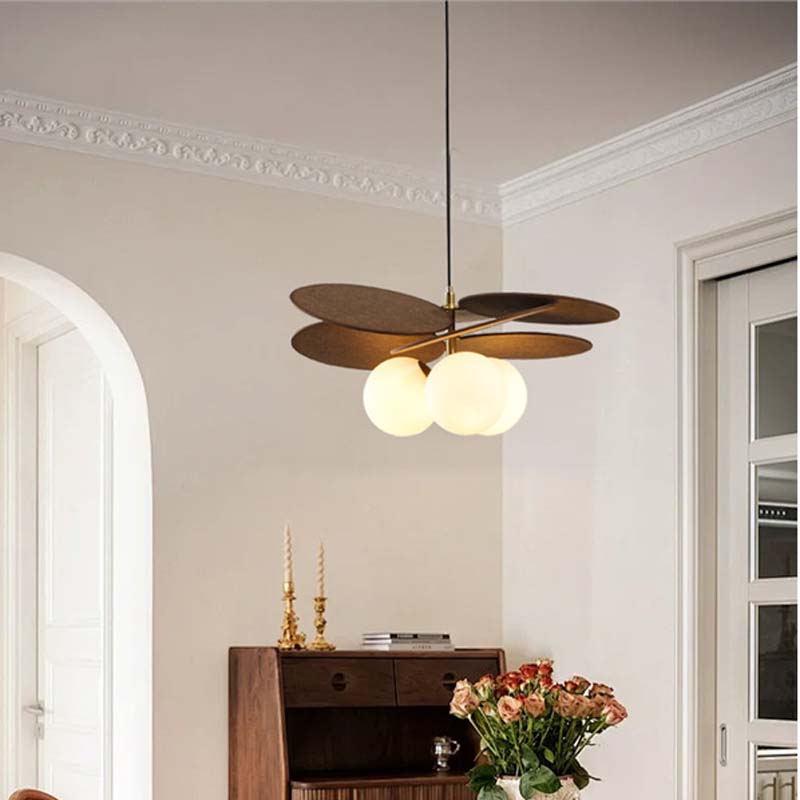 Pendant light with wooden petal elements and frosted glass globes in an interior.
