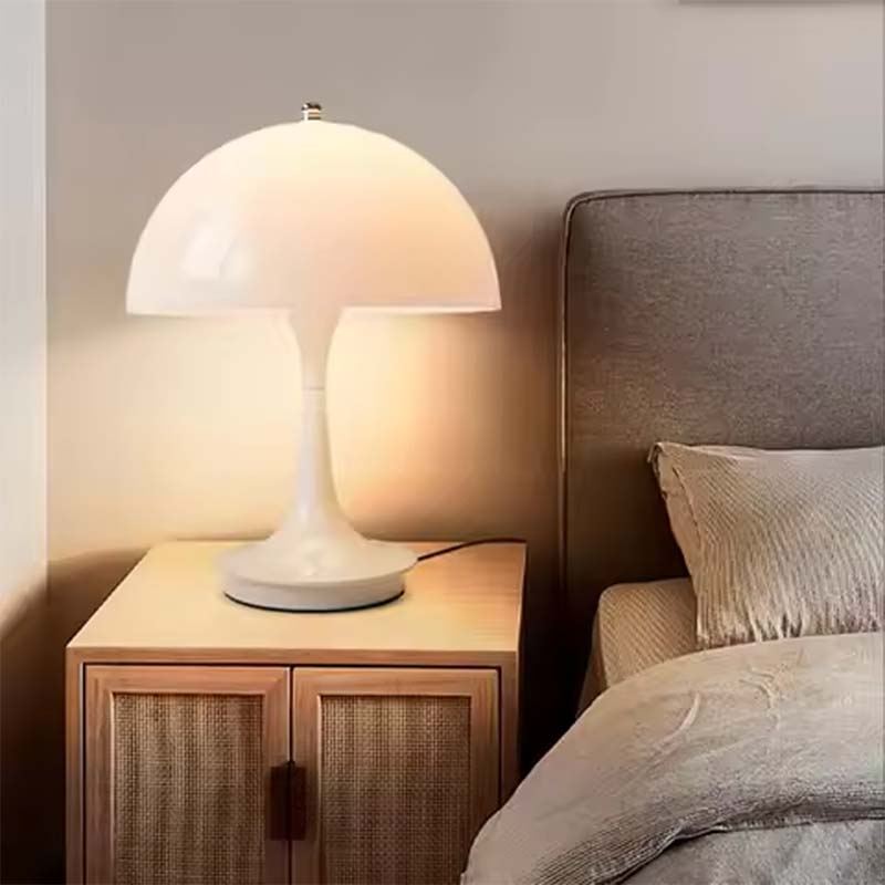 Table lamp on a nightstand next to a bed with neutral bedding.
