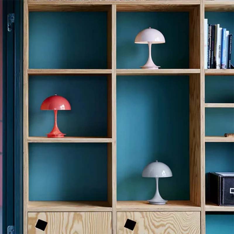Wooden shelves with colorful lamps against a teal wall