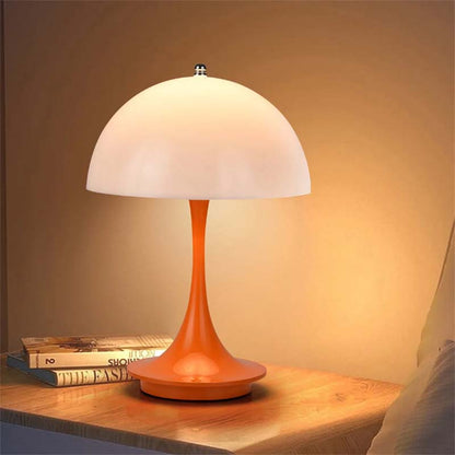 Table lamp with a white shade and orange base on a wooden surface.