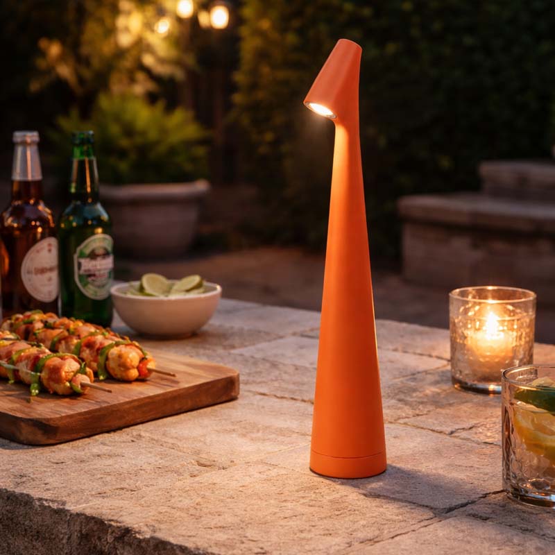 Orange outdoor lamp on a table with food and drinks in a garden setting