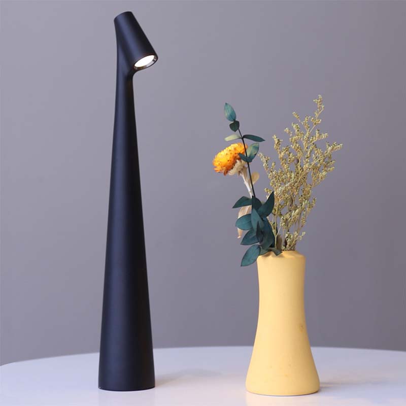 Black table lamp and yellow vase with flowers on gray background