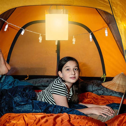 A child in a tent with a laptop and a hanging Portable Touch Control LED Bedside Night Light in a camping tent.