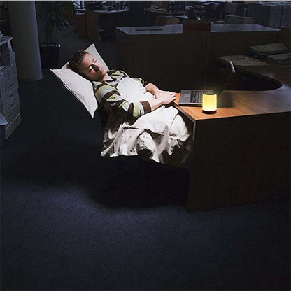 Person lying on a bean bag chair in a dimly lit room with a lamp on a table.