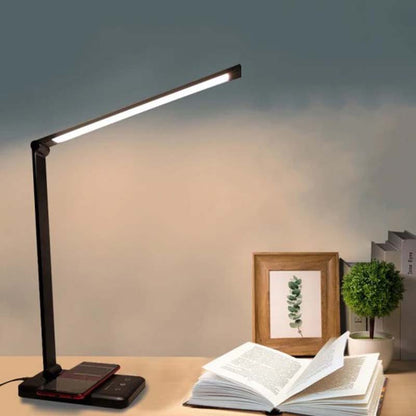 Desk lamp on a table with an open book and decorative items in the background
