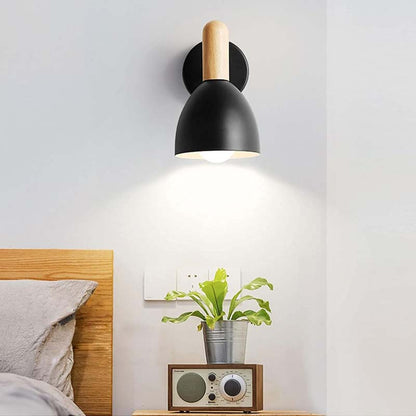 Modern wall lamp with wooden accent on a white wall above a bed.