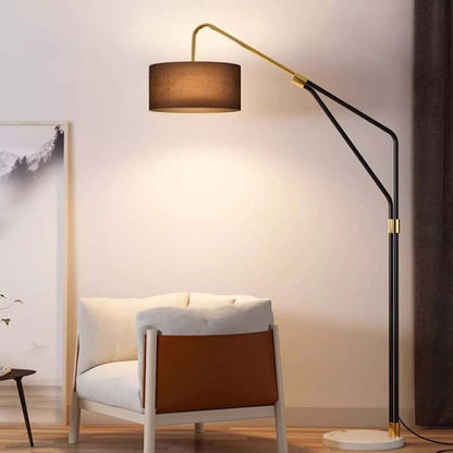 Modern floor lamp with a brown shade next to a white armchair in a room.