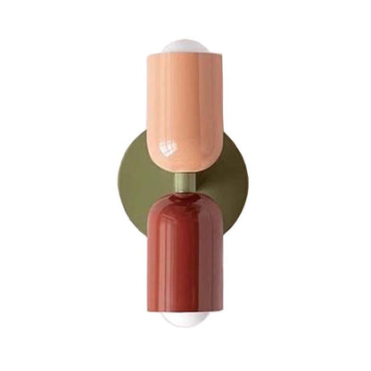 Wall sconce with a peach-colored top and red base on a white background