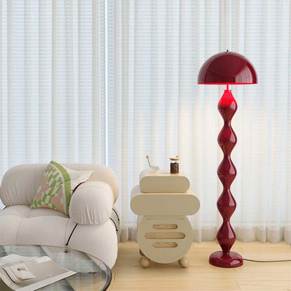 Red floor lamp in a living room setting with a beige armchair and side table.