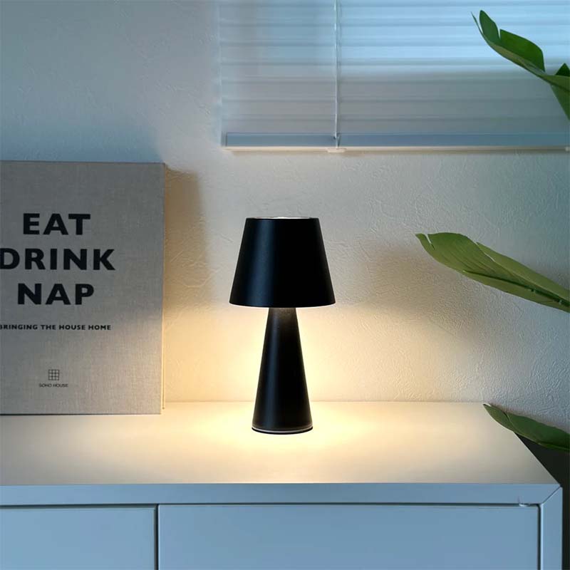 Black table lamp on a white surface with a motivational poster in the background