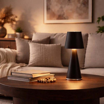Black table lamp on a wooden table in a cozy living room setting.