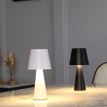 Two table lamps, one with a white shade and the other with a black shade, on a wooden surface.