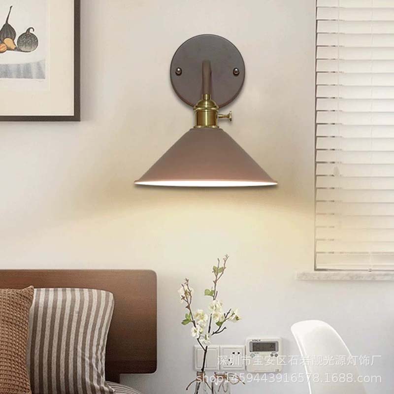 Wall-mounted lamp with brown shade and gold fixture in a room setting.
