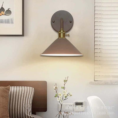 Wall-mounted lamp with brown shade and gold fixture in a room setting.