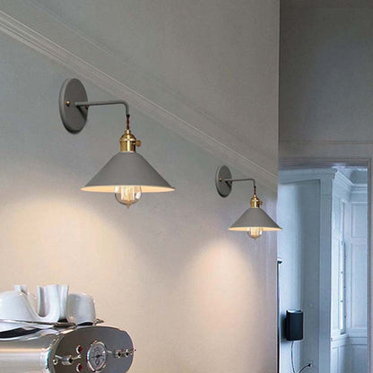 Two wall-mounted lights on a light gray wall with a blurred room in the background.