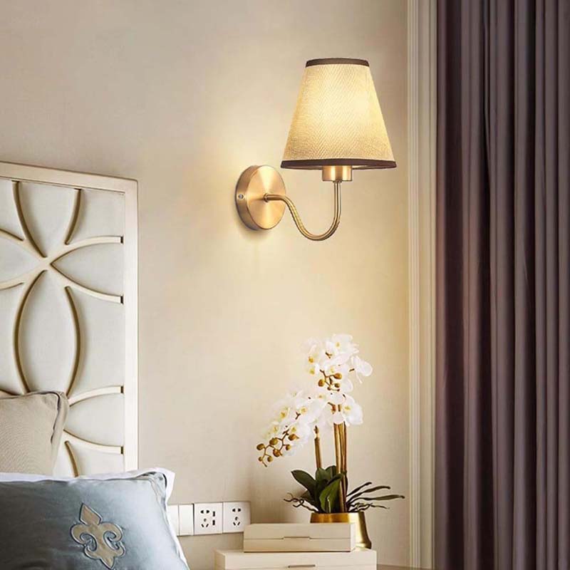 Wall-mounted lamp with a decorative headboard and plant in a bedroom setting