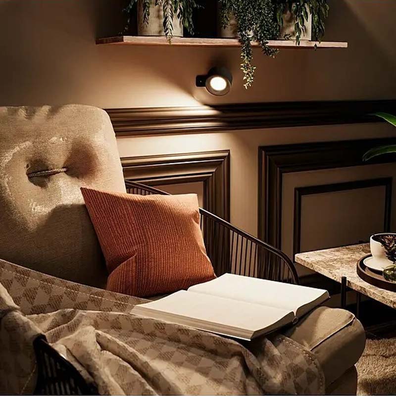 Touch LED Wall Sconce in a cozy living room with an armchair, a book and decorative elements.