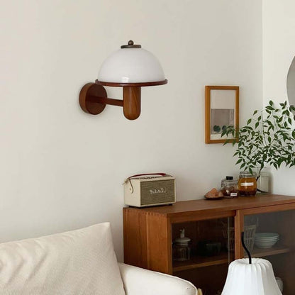 Wall lamp on a wall above a wooden sideboard with a radio and decorative items.