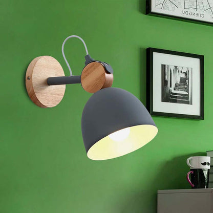 Wall-mounted lamp with wooden base and gray shade on a green wall.