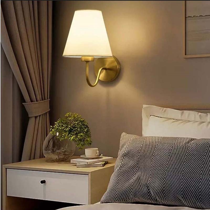 Bedroom interior with a wall lamp, nightstand, and bed.