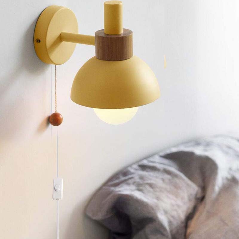 Yellow wall lamp with wooden accents on a white wall.