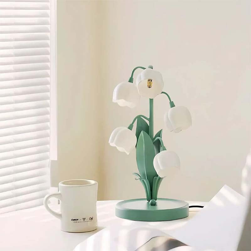 Decorative table lamp with flower design on a white surface next to a mug.