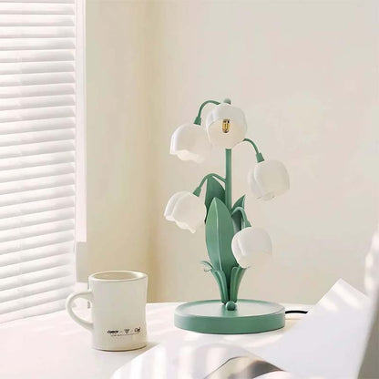 Decorative table lamp with flower design on a white surface next to a mug.