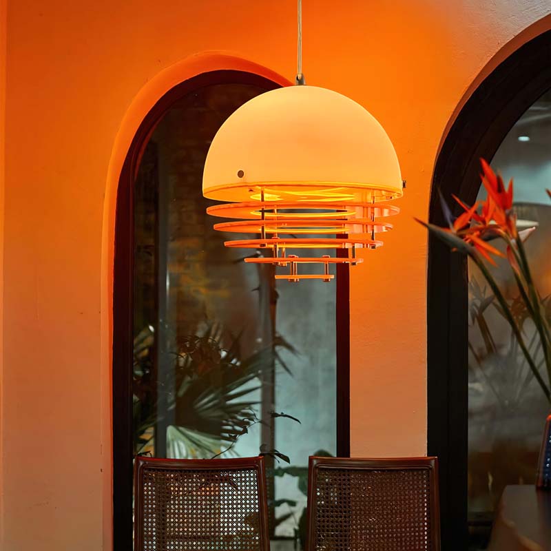 Sunset pendant light turned on with warm glow in a cozy interior with arched windows.