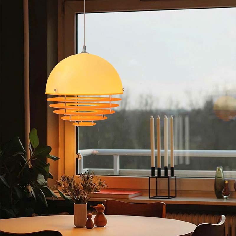 Sunset pendant light turned on with warm glow near a window with outdoor view.