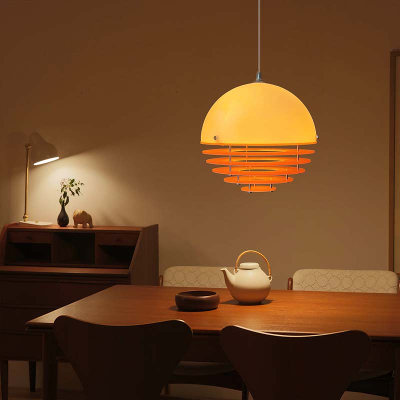 Sunset pendant light with warm light above a wooden dining table in a cozy interior