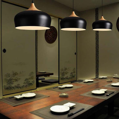 Dining room with black pendant lights, wooden table, and decorative plates.