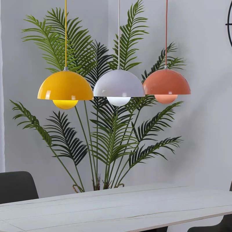 Three colorful pendant lights hanging above a table with plants in the background.