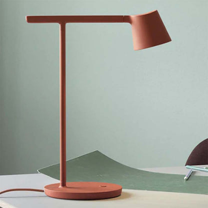 Modern red table lamp on a light green surface with a neutral background