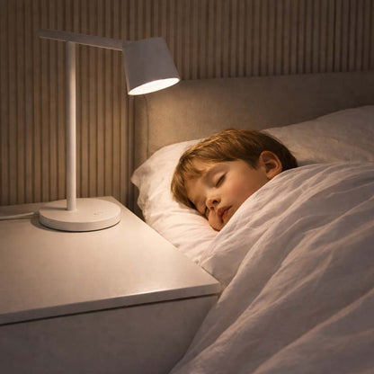 Child sleeping in bed with a nightstand lamp on