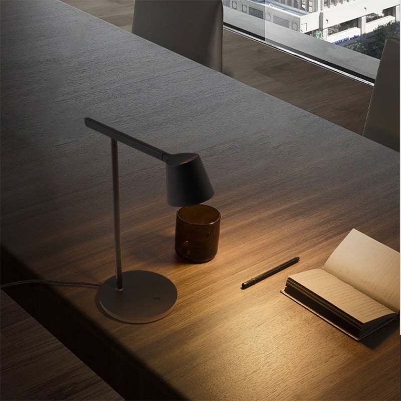Desk with a lamp, pen, and notebook in a modern office setting