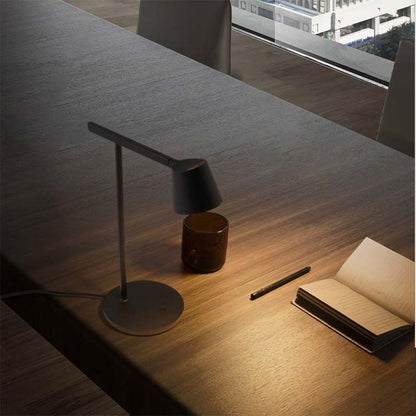 Desk with a lamp, pen, and notebook in a modern office setting