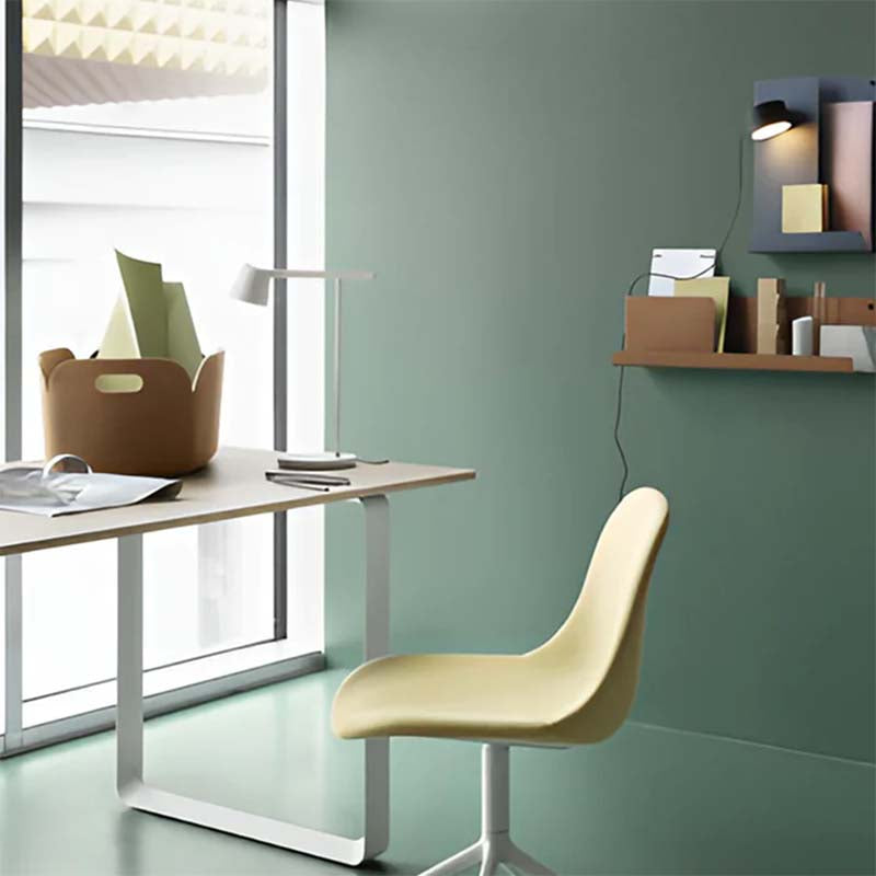 Modern office desk with chair and LED table lamp against green wall background.