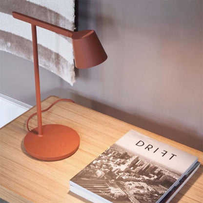 Orange desk lamp on a wooden surface next to a book titled 'DRIFT'.